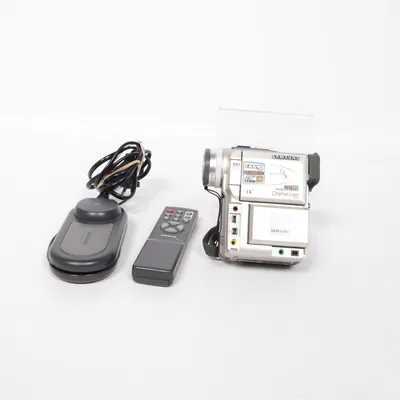 Videokamera (Vp-D190i, miniDV camcorder, miniDV camera, vintage camcorder, retro camera, digital camcorder, Samsung camcorder, Samsung VP-D190i, tape camera, tape camcorder, Y2K tech, nostalgic tech, old school camera, filming camera, home video camera, vintage electronics, retro gadget, collectible camera, videography, filming gear, video recorder, digital video camera, DV camera, camcorder aesthetic, early 2000s tech, rare electronics, retro filming, analog aesthetic, memory recording, travel camera, zoom camera, vintage tech collector, home movie camera, silver camcorder, media transfer, FireWire camera, IEEE 1394, miniDV transfer, old camera gear, retro media, filming equipment, nostalgia, vintage Samsung, collectible electronics, working camera, rare camera, old tech, retro aesthetic, Y2K gadget, video transfer, classic camcorder) från Samsung